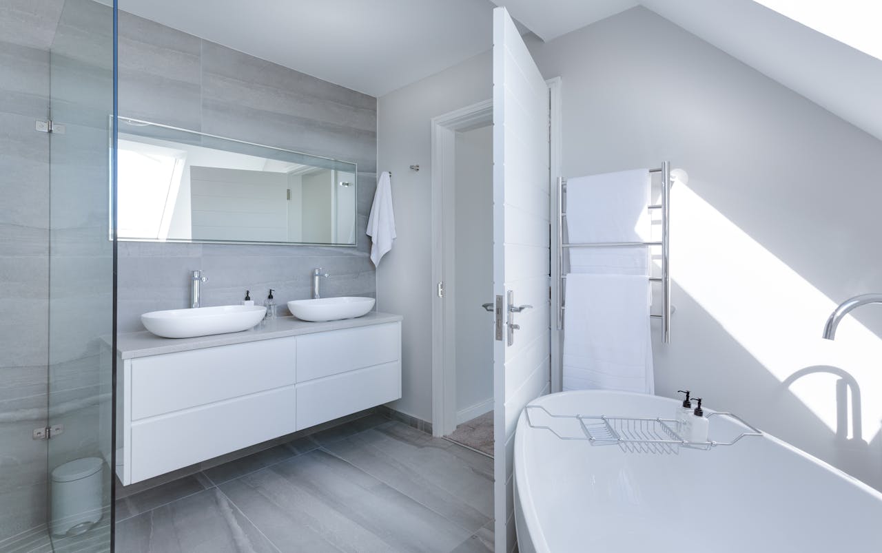 Sleek contemporary bathroom with bathtub and twin sinks, showcasing minimalist design and luxury.